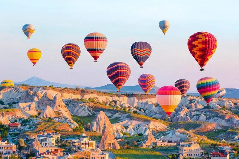 Bunte Heißluftballons über den Felsformationen und der Stadt in Kappadokien